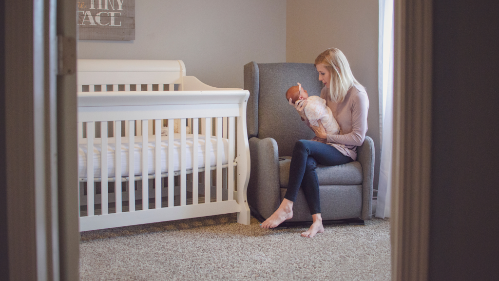 Woman in a nursery with her newborn, a newly set up nursery for her newborn baby